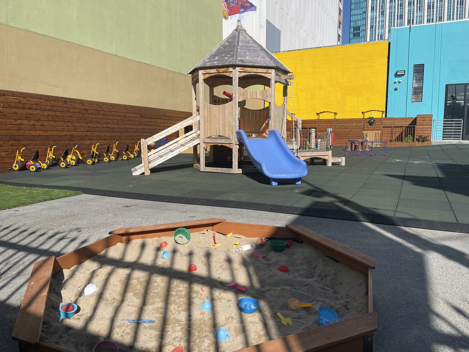 Apple Tree's outdoor playground with a wooden play structure, slide and sandbox