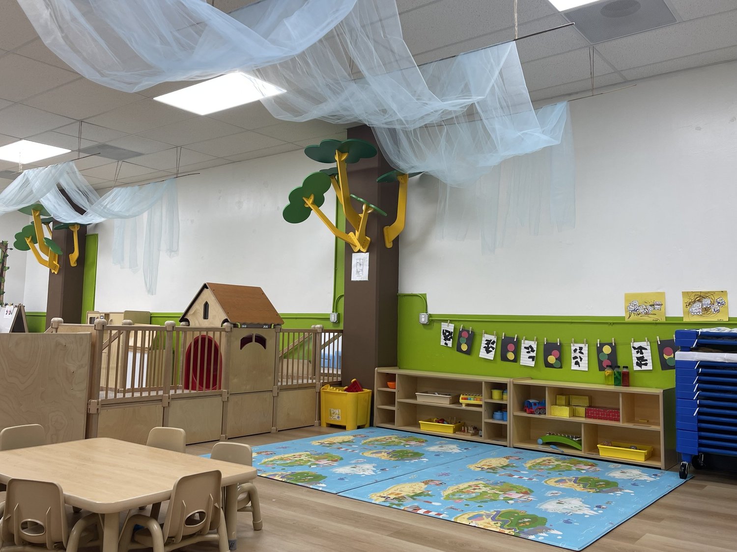 A play-house corner of an Apple Tree classroom with a wooden cottage and reading area