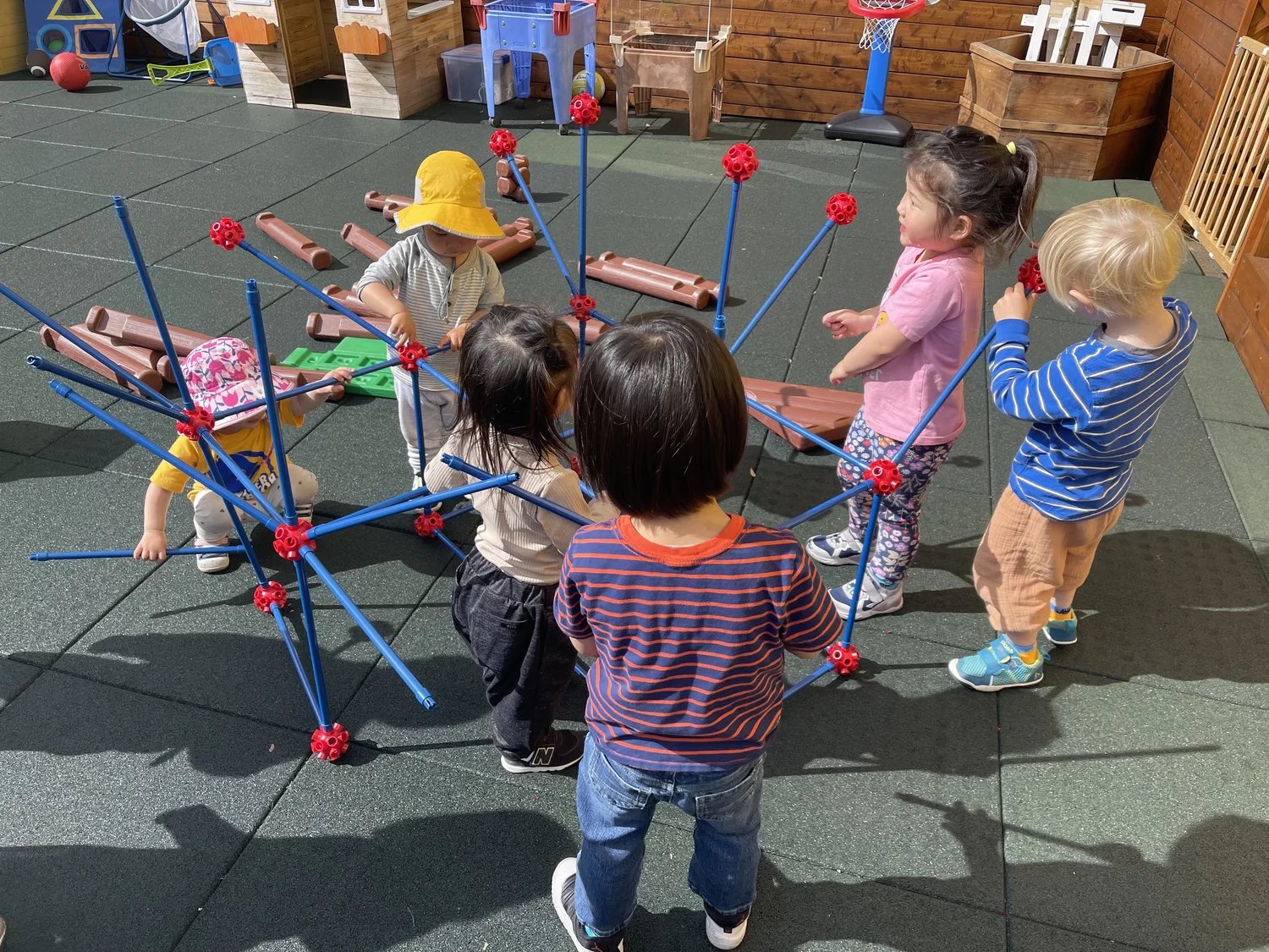 Children playing with a large blue construction toy on the Apple Tree playground